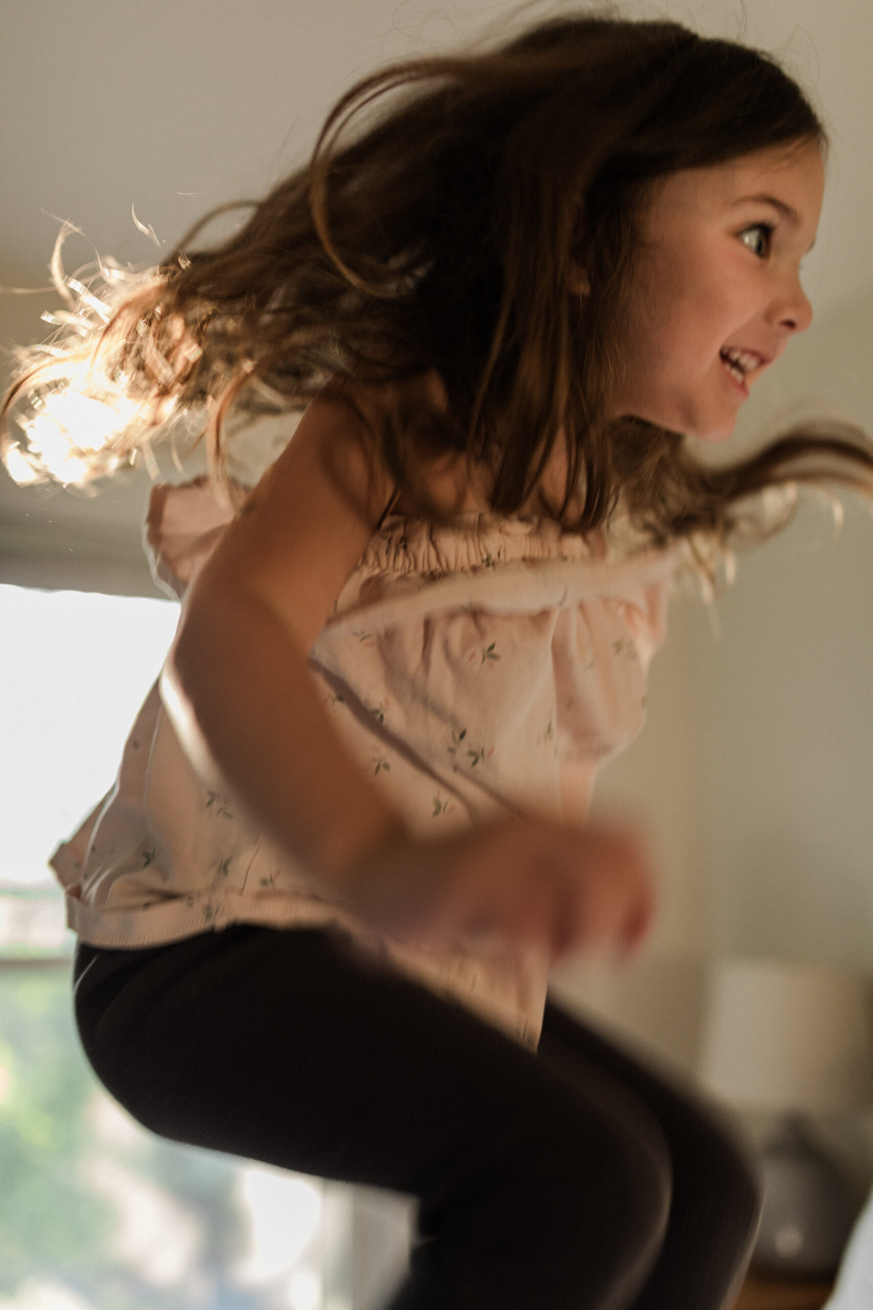 Young girl jumping on bed